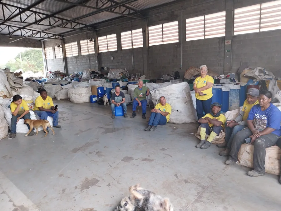 Equipe de cooperados reunida no galpão da cooperativa de reciclagem