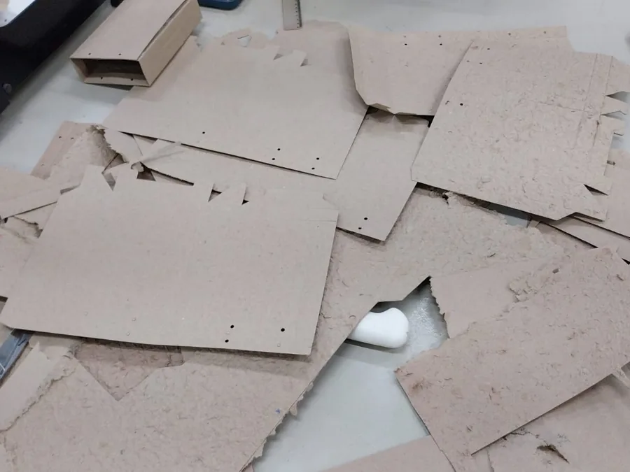 Recortes de papel reciclado sobre a bancada, no desenho do produto