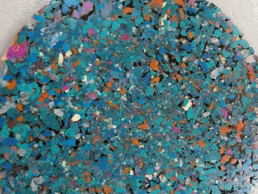 Disco de plástico reciclado prensado, com fragmentos coloridos visíveis
